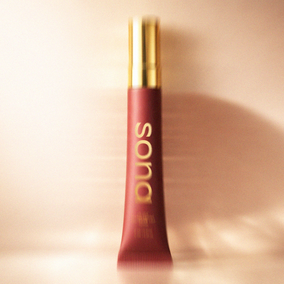 Red lip balm tube with gold cap on a beige background